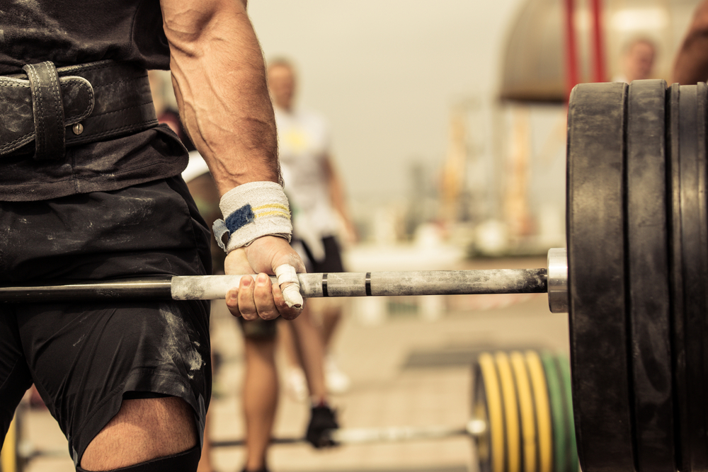 Closeup portrait of professional bodybuilder workout with barbell outdoors