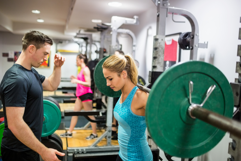 Fit woman lifting heavy barbell in weights room at the gym Fit woman lifting heavy barbell in weights room at the gym